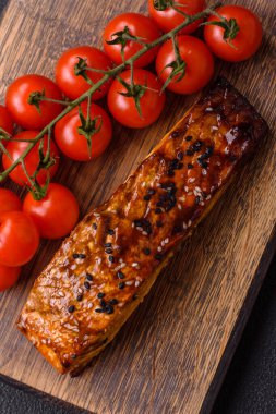 Sos ve susamlı lezzetli kırmızı somon balığı, koyu beton arka planda baharatlar ve otlar.