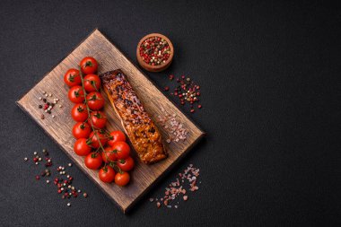 Sos ve susamlı lezzetli kırmızı somon balığı, koyu beton arka planda baharatlar ve otlar.