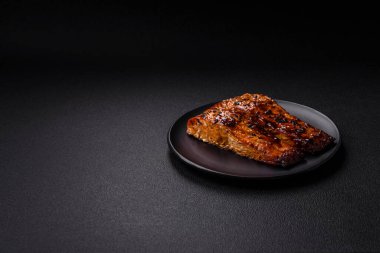 Sos ve susamlı lezzetli kırmızı somon balığı, koyu beton arka planda baharatlar ve otlar.