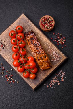 Sos ve susamlı lezzetli kırmızı somon balığı, koyu beton arka planda baharatlar ve otlar.