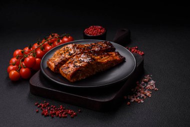 Sos ve susamlı lezzetli kırmızı somon balığı, koyu beton arka planda baharatlar ve otlar.