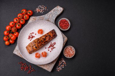 Sos ve susamlı lezzetli kırmızı somon balığı, koyu beton arka planda baharatlar ve otlar.