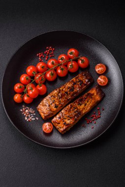 Sos ve susamlı lezzetli kırmızı somon balığı, koyu beton arka planda baharatlar ve otlar.