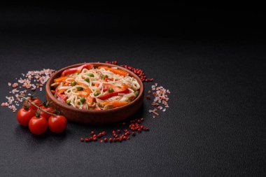 Lezzetli pirinç eriştesi veya koyu beton bir arka planda tavuk, havuç, biber, tuz, baharat ve otlarla udon.