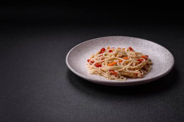 Lezzetli pirinç eriştesi veya koyu beton bir arka planda tavuk, havuç, biber, tuz, baharat ve otlarla udon.