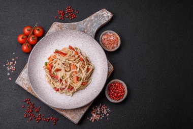 Lezzetli pirinç eriştesi veya koyu beton bir arka planda tavuk, havuç, biber, tuz, baharat ve otlarla udon.