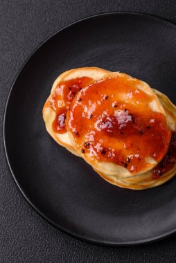 Koyu beton bir zeminde seramik tabakta lezzetli reçelli taze pişmiş krep.