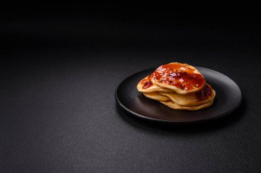 Koyu beton bir zeminde seramik tabakta lezzetli reçelli taze pişmiş krep.