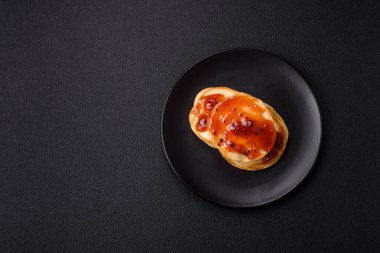 Koyu beton bir zeminde seramik tabakta lezzetli reçelli taze pişmiş krep.