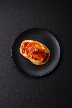 Koyu beton bir zeminde seramik tabakta lezzetli reçelli taze pişmiş krep.