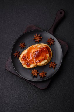 Koyu beton bir zeminde seramik tabakta lezzetli reçelli taze pişmiş krep.