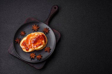 Koyu beton bir zeminde seramik tabakta lezzetli reçelli taze pişmiş krep.