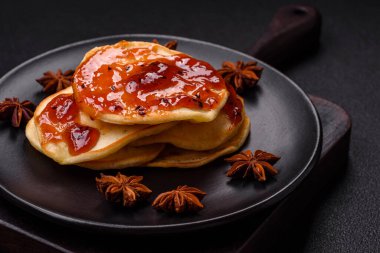 Koyu beton bir zeminde seramik tabakta lezzetli reçelli taze pişmiş krep.