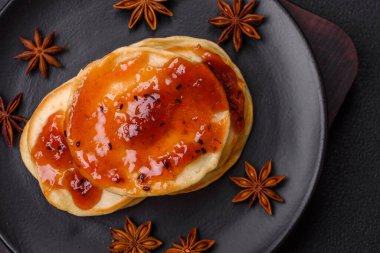 Koyu beton bir zeminde seramik tabakta lezzetli reçelli taze pişmiş krep.