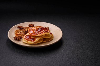 Koyu beton bir zeminde seramik tabakta lezzetli reçelli taze pişmiş krep.