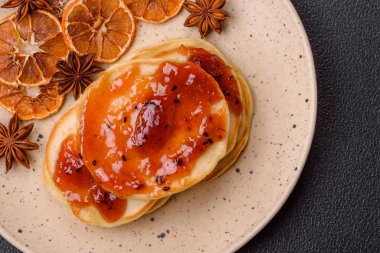 Koyu beton bir zeminde seramik tabakta lezzetli reçelli taze pişmiş krep.