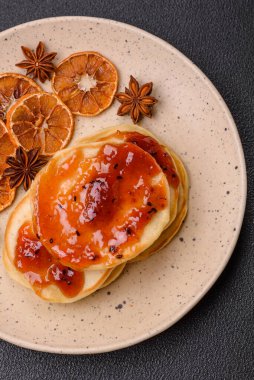 Koyu beton bir zeminde seramik tabakta lezzetli reçelli taze pişmiş krep.