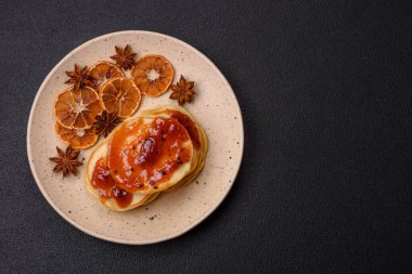 Koyu beton bir zeminde seramik tabakta lezzetli reçelli taze pişmiş krep.