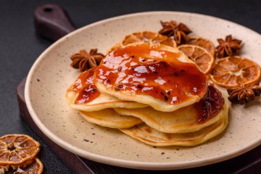 Koyu beton bir zeminde seramik tabakta lezzetli reçelli taze pişmiş krep.