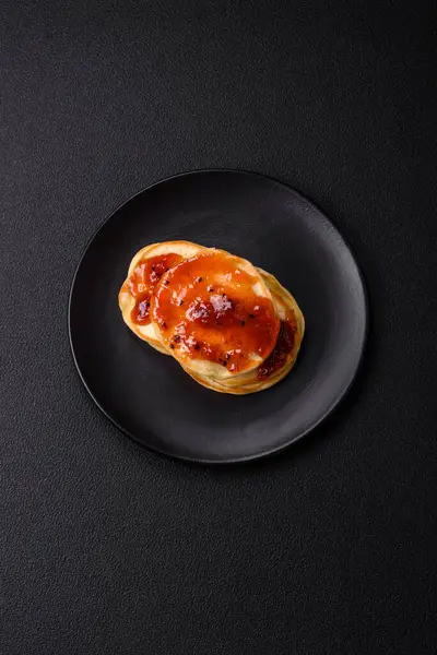 Koyu beton bir zeminde seramik tabakta lezzetli reçelli taze pişmiş krep.