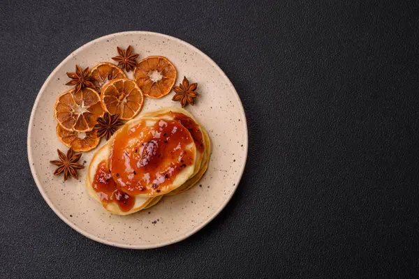 Koyu beton bir zeminde seramik tabakta lezzetli reçelli taze pişmiş krep.