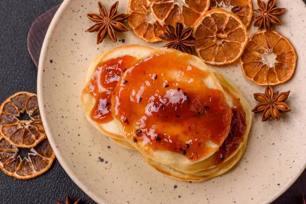 Koyu beton bir zeminde seramik tabakta lezzetli reçelli taze pişmiş krep.