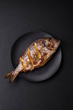 Izgarada pişirilmiş leziz dorado. Koyu dokulu arka planda tuz, baharat ve otlarla.