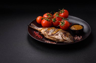 Izgarada pişirilmiş leziz dorado. Koyu dokulu arka planda tuz, baharat ve otlarla.