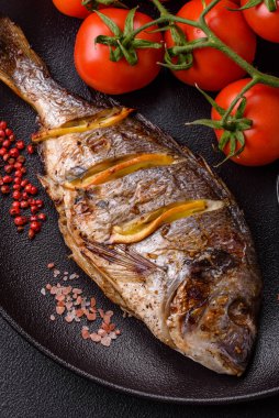 Izgarada pişirilmiş leziz dorado. Koyu dokulu arka planda tuz, baharat ve otlarla.