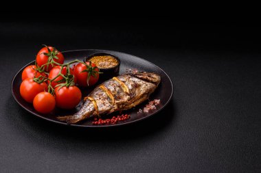 Izgarada pişirilmiş leziz dorado. Koyu dokulu arka planda tuz, baharat ve otlarla.