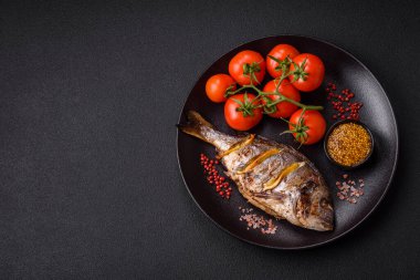 Izgarada pişirilmiş leziz dorado. Koyu dokulu arka planda tuz, baharat ve otlarla.