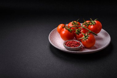 Koyu beton arka planda bir dalda taze kırmızı kiraz domatesleri evde yemek hazırlamak için bir malzeme olarak kullanılıyor.
