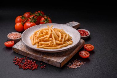 Koyu beton bir arka planda tuzlu ve baharatlı lezzetli çıtır altın kızartmalar.