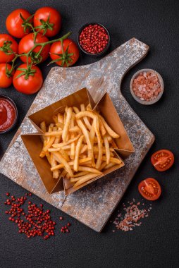 Koyu beton bir arka planda tuzlu ve baharatlı lezzetli çıtır altın kızartmalar.