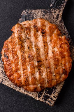 Lezzetli taze ızgara tavuk filetosu, esrarlı baharatlar ve çimento kaplı otlar. Ateşte pişirilmiş bir tabak.