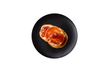 Koyu beton bir zeminde seramik tabakta lezzetli reçelli taze pişmiş krep.