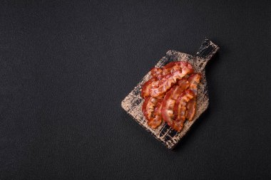 Koyu bir arka planda tuzlu ve baharatlı leziz kızarmış domuz pastırması sağlıklı bir kahvaltı hazırlamak için bir malzeme.