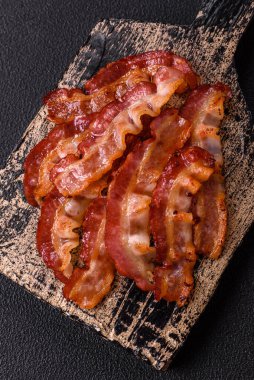 Koyu bir arka planda tuzlu ve baharatlı leziz kızarmış domuz pastırması sağlıklı bir kahvaltı hazırlamak için bir malzeme.