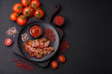 Koyu bir arka planda tuzlu ve baharatlı leziz kızarmış domuz pastırması sağlıklı bir kahvaltı hazırlamak için bir malzeme.