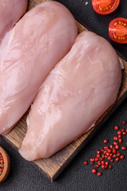 Koyu beton bir masada baharat ve otlarla taze tavuk filetosu. Et yemekleri için hazırlık.