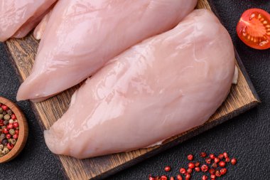 Koyu beton bir masada baharat ve otlarla taze tavuk filetosu. Et yemekleri için hazırlık.