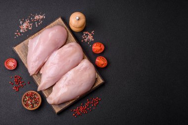 Koyu beton bir masada baharat ve otlarla taze tavuk filetosu. Et yemekleri için hazırlık.