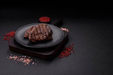 Karanlık bir arka planda taze sulu lezzetli biftek. Baharatlı ve otlu et yemeği.