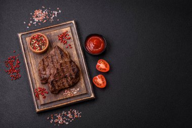 Karanlık bir arka planda taze sulu lezzetli biftek. Baharatlı ve otlu et yemeği.