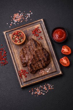 Karanlık bir arka planda taze sulu lezzetli biftek. Baharatlı ve otlu et yemeği.