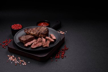 Karanlık bir arka planda taze sulu lezzetli biftek. Baharatlı ve otlu et yemeği.