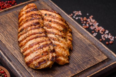 Lezzetli taze ızgara tavuk filetosu, esrarlı baharatlar ve çimento kaplı otlar. Ateşte pişirilmiş bir tabak.