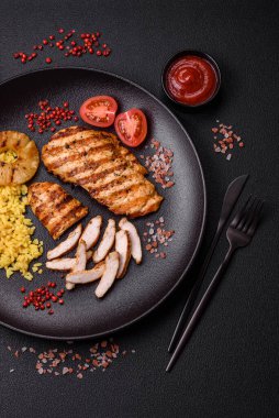 Lezzetli taze ızgara tavuk filetosu, esrarlı baharatlar ve çimento kaplı otlar. Ateşte pişirilmiş bir tabak.