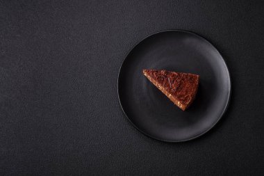 Lezzetli taze cheesecake keki ya da koyu beton arka planda seramik tabakta kremalı ve fındıklı snickers.