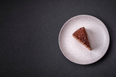 Lezzetli taze cheesecake keki ya da koyu beton arka planda seramik tabakta kremalı ve fındıklı snickers.